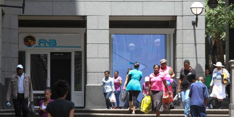 Pedestrians pass the headquarters of First National Bank (FNB), a division of FirstRand Bank Ltd., in Johannesburg.