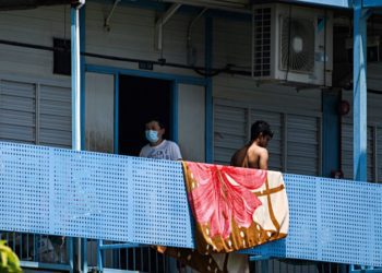 A man, wearing a face mask walks along corridor of Tuas South foreign workers dormitory that has been placed under government restriction as preventive measure against the spread of the COVID-19 coronavirus in Singapore on April 19, 2020. - Singapore imposed a mandatory stay-home order for migrant workers including in the construction sector for 14 days effective on April 20 due to coronavirus pandemic. (Photo by Roslan RAHMAN / AFP) (Photo by ROSLAN RAHMAN/AFP via Getty Images)