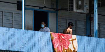 A man, wearing a face mask walks along corridor of Tuas South foreign workers dormitory that has been placed under government restriction as preventive measure against the spread of the COVID-19 coronavirus in Singapore on April 19, 2020. - Singapore imposed a mandatory stay-home order for migrant workers including in the construction sector for 14 days effective on April 20 due to coronavirus pandemic. (Photo by Roslan RAHMAN / AFP) (Photo by ROSLAN RAHMAN/AFP via Getty Images)