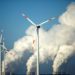 Steam billows from coal power station behind wind turbines