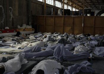 Survivors of a shipwreck sleep at a warehouse at the port in Kalamata town, about 240 kilometers (150 miles) southwest of Athens, Wednesday, June 14, 2023.