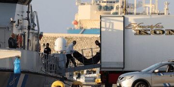 Rescue workers carry bodies from a coast guard vessel to a refrigerated truck at the port in Kalamata town.