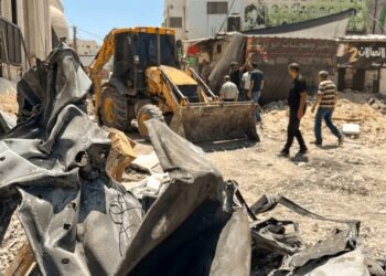 Palestinians walk on a damaged road in the Jenin Refugee Camp in the West Bank.