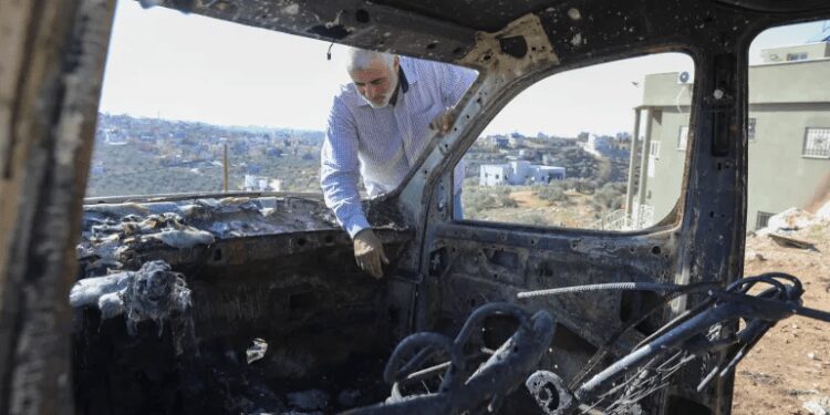 Countries Decry Israeli Settler Violence Against Palestinians 1 A Palestinian checks a car burned in an Israeli settler raid near Salfit.