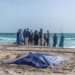 Bystanders look at covered bodies of migrants who perished in a shipwreck off the coast of Mauritania
