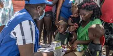 A UN staff member provides medical care to a displaced woman and children.
