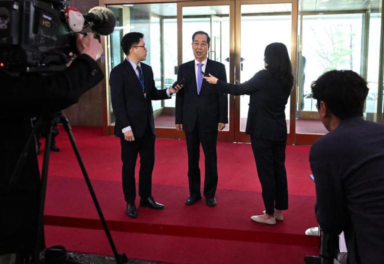 South Korean Prime Minister Han Duck-soo speaks to the media as he arrives at the Government Complex in Seoul on March 24, 2025, after the Constitutional Court dismissed his impeachment.