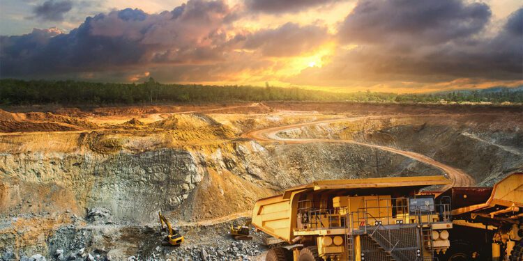 Yellow dump truck loading minerals gold at mining quarry.