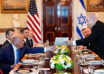 Israel's Prime Minister Benjamin Netanyahu hands President Donald Trump a folder during a meeting in the Blue Room of the White House, Monday,