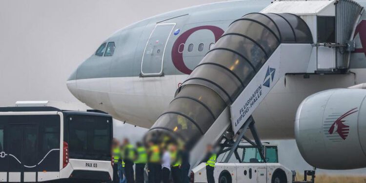 People board a Qatar Airways plane.
