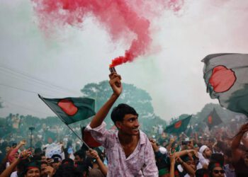 People use coloured smoke and wave flags as they celebrate the one year anniversary since student-led protests ousted Bangladesh's former Prime Minister Sheikh Hasina, at Manik Mia Avenue, outside of the parliament building, in Dhaka, Bangladesh, August 5, 2025.