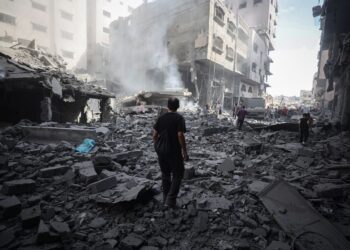 Palestinians walk through debris after an Israeli attack near Abbas Junction in Gaza City on Friday.