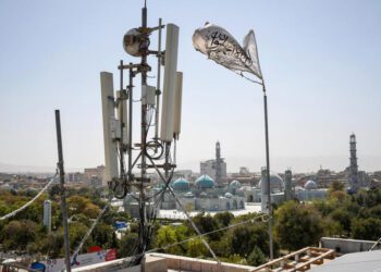 A Taliban flag flutters near telecom equipment installed over a rooftop providing internet services overlooking Hazrat-e-Ali Shrine, or Blue Mosque, in Mazar-i-Sharif on September 16, 2025, as the Taliban administration banned fibre-optic internet in Balkh province.