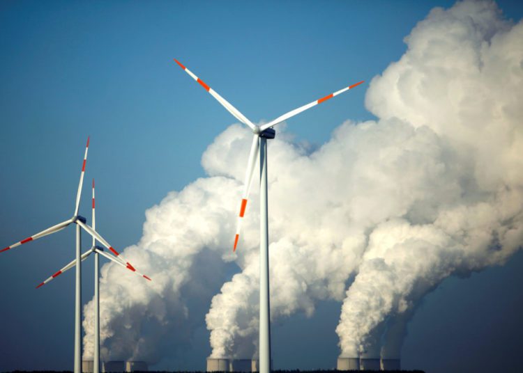 Don’t Rush With Energy Transition; Energy Expert Advices 1 Steam billows from coal power station behind wind turbines