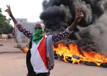 A Sudanese protestant in front of burning tyres during the protest