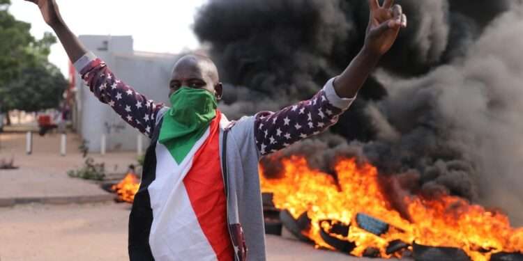 A Sudanese protestant in front of burning tyres during the protest