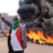 A Sudanese protestant in front of burning tyres during the protest