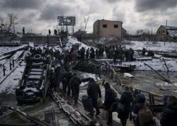 Ukrainians cross an improvised path under a destroyed bridge while fleeing Irpin, in the outskirts of Kyiv, Ukraine, Tuesday, March 8, 2022