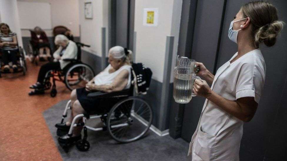 A medical staff member brings water to residents in a retirement home in