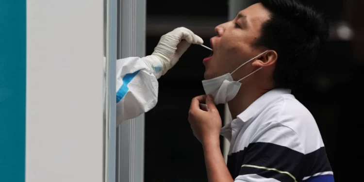 A medical worker takes a swab sample from a person at a mobile nucleic acid testing booth, following the coronavirus outbreak in Beijing [Tingshu WangReuters]