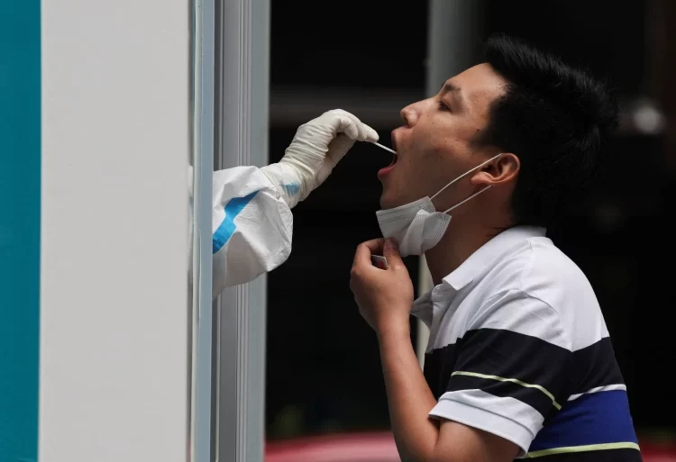 A medical worker takes a swab sample from a person at a mobile nucleic acid testing booth, following the coronavirus outbreak in Beijing [Tingshu WangReuters]
