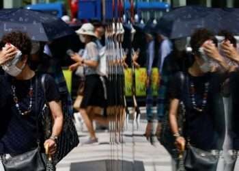 A woman wipes her face as she walks down a street in Tokyo