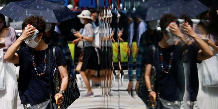 A woman wipes her face as she walks down a street in Tokyo