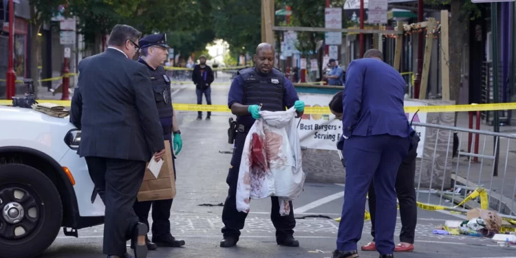 Members of the police force inspect evidence at the scene of the crime on South Street, Philadelphia, June 5, 2022. © Michael Perez, AP