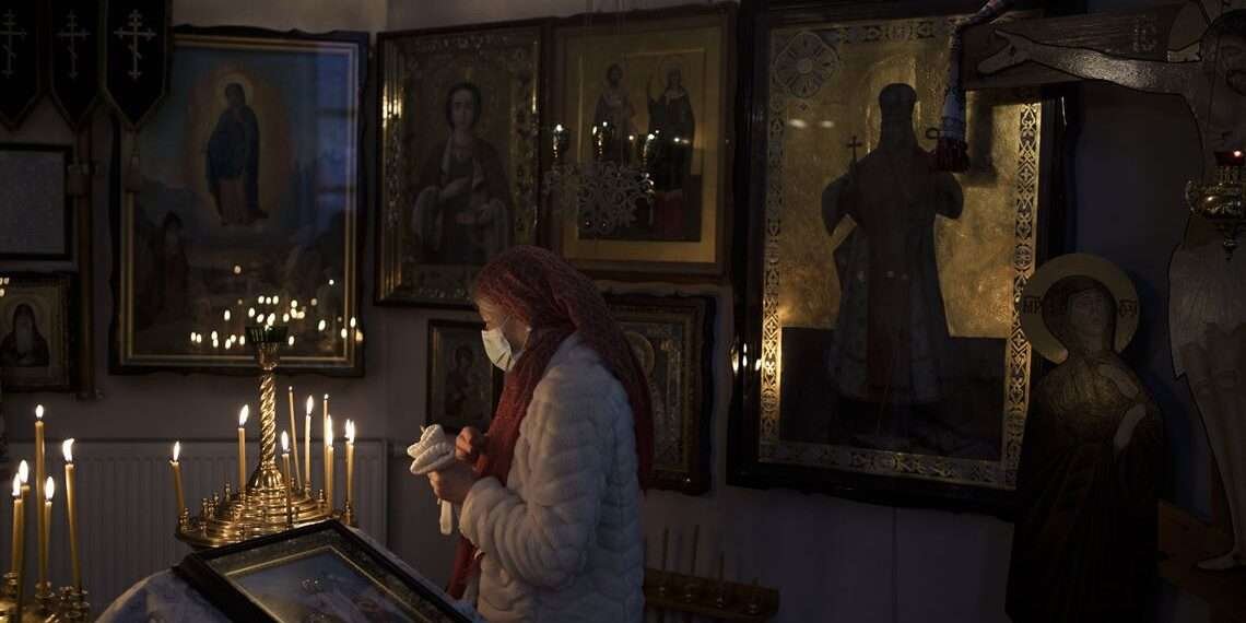 A woman attends a Christmas mass at an Orthodox Church in Bobrytsia, outskirts of Kyiv, Ukraine, Sunday, Dec. 25, 2022.