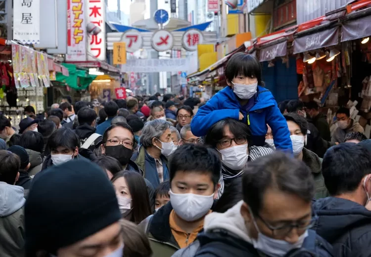 People wearing face masks flock to a shopping street famous for a year-end shopping before New Year holidays in Tokyo, Friday, Dec. 30, 2022.