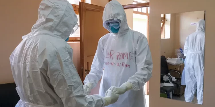 Doctors wearing protective equipment pray together before they visit a patient who was in contact with an Ebola victim, in the isolation section of Entebbe Regional Referral Hospital in Entebbe, Uganda on Oct. 20, 2022.