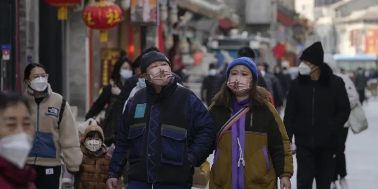 Visitors wearing face masks tour a pedestrian shopping street at Qianmen walking street in Beijing, Tuesday, Jan. 3, 2023.
