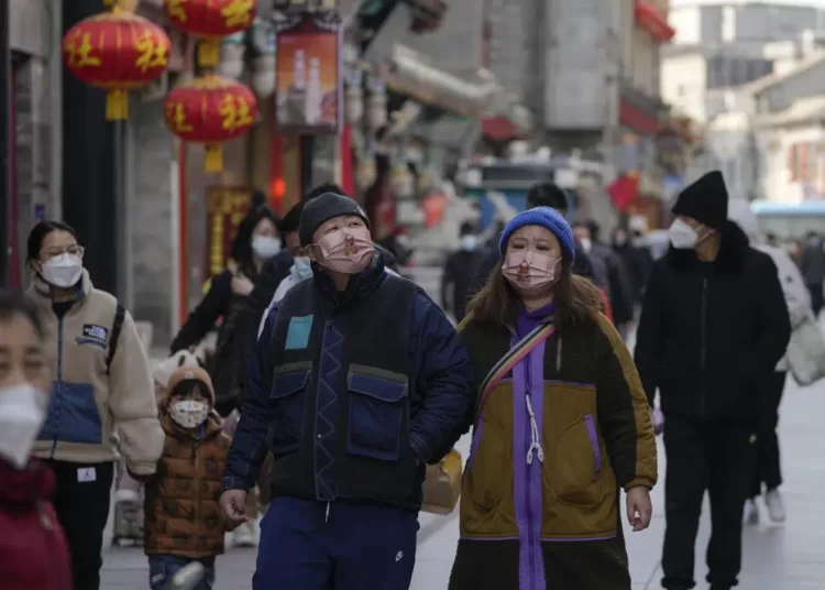 Visitors wearing face masks tour a pedestrian shopping street at Qianmen walking street in Beijing, Tuesday, Jan. 3, 2023.