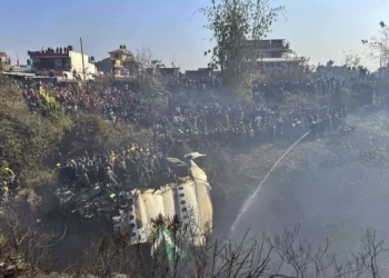 Locals watch the wreckage of a passenger plane as rescuers search the crash site, in Pokhara, Nepal.