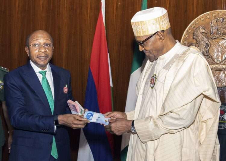 In this photo released by the Nigeria State House, Nigeria's central bank governor, Godwin Emefile, left, presents the newly designed currency notes to Nigeria's President Muhammadu Buhari, right, during a launch in Abuja, Nigeria