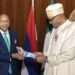 In this photo released by the Nigeria State House, Nigeria's central bank governor, Godwin Emefile, left, presents the newly designed currency notes to Nigeria's President Muhammadu Buhari, right, during a launch in Abuja, Nigeria