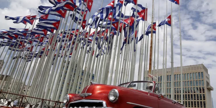 A classic American convertible car passes beside the United States embassy as Cuban flags fly at the Anti-Imperialist Tribune, a massive stage on the Malecon seaside promenade in Havana, Cuba, July 26, 2015.
