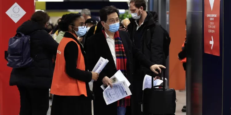 Passengers arriving from China wait in front of a COVID-19 testing area set at the Roissy Charles de Gaulle airport, north of Paris, Sunday, Jan. 1, 2023.