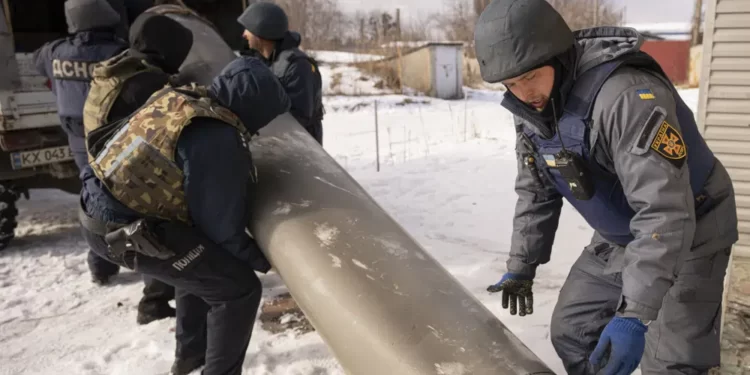 Ukrainian emergency services employees push the remains of an S-300 missile fired by Russian forces onto a truck in Kharkiv, Ukraine, Friday, Feb. 17, 2023.