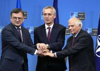 From left, Ukraine's Foreign Minister Dmytro Kuleba, NATO Secretary General Jens Stoltenberg and European Union foreign policy chief Josep Borrell join hands after addressing a media conference at NATO headquarters in Brussels, Tuesday, Feb. 21, 2023.