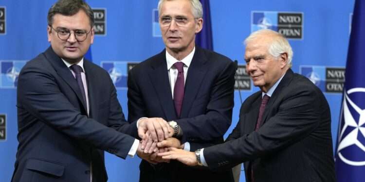 From left, Ukraine's Foreign Minister Dmytro Kuleba, NATO Secretary General Jens Stoltenberg and European Union foreign policy chief Josep Borrell join hands after addressing a media conference at NATO headquarters in Brussels, Tuesday, Feb. 21, 2023.