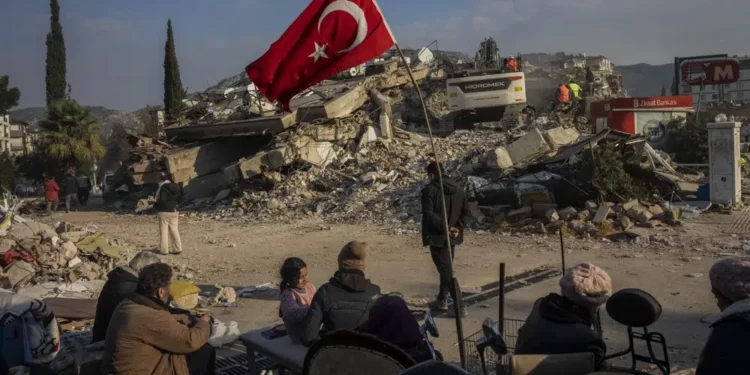 <strong>Turkey-Syria Earthquake: At Least 98 People Arrested For Alleged Looting</strong> 1 A family sit next to a collapsed building as they wait for the bodies of their relatives to be recovered from under the rubble in Antakya, southeastern Turkey