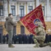 Ukrainian President Volodymyr Zelenskyy, left, holds the flag of a military unit as an officer kisses it, during commemorative event on the occasion of the Russia Ukraine war one year anniversary in Kyiv, Ukraine, Friday, Feb. 24, 2023.