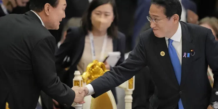 Japan's Prime Minister Fumio Kishida, right, shakes hands with South Korea's President Yoon Suk Yeol during the ASEAN - East Asia Summit in Phnom Penh, Cambodia, on Nov. 13, 2022