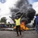 rotesters react next to a burning barricade during a mass rally called by the opposition leader Raila Odinga over the high cost of living, in Kibera Slum, Nairobi, Kenya, Thursday, March 30, 2023.
