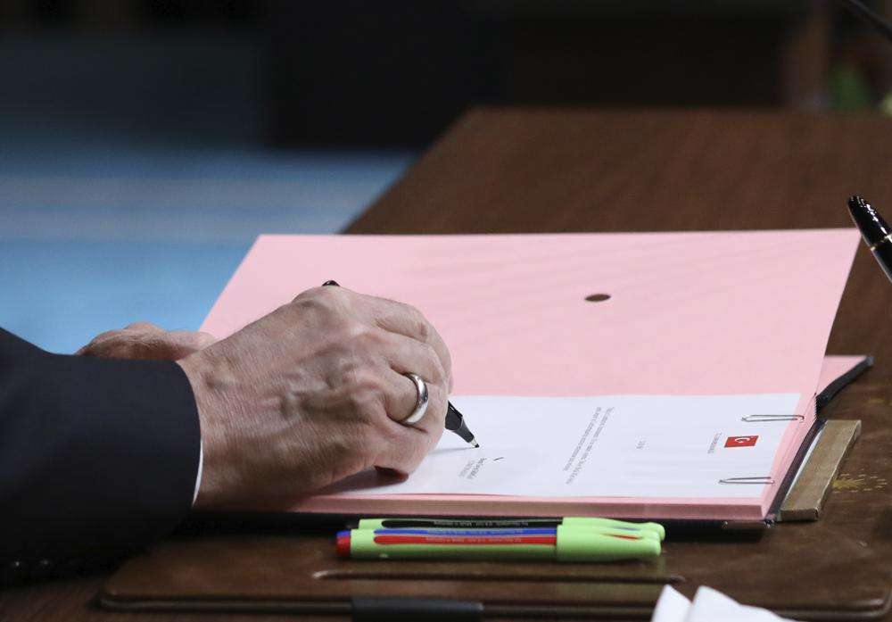 President Recep Tayyip Erdogan puts his signature on a decision confirming the election date