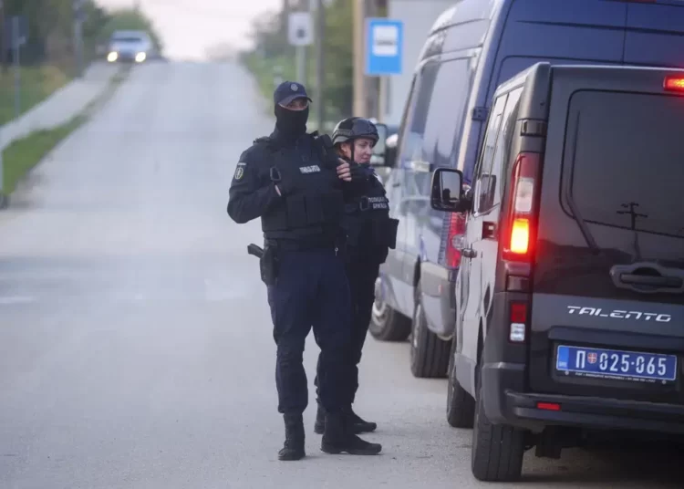 Police officers stand guard on a road in the village of Dubona, some 50 kilometers (30 miles) south of Belgrade, Serbia, Friday, May 5, 2023, as they block the road near the scene of a Thursday night attack.