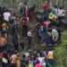 Migrants stand on the bank of the Rio Grande river as Texas National Guards block them from behind razor wire, seen from Matamoros, Mexico, Thursday, May 11, 2023.