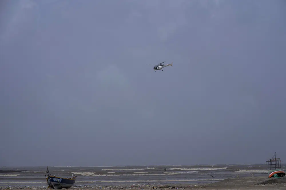 An Indian Coast Guard helicopter flies during high tide at the Juhu beach