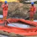 In this grab taken from video, workers stand by a container to collect oil spill waste, in Ogoniland, Nigeria.
